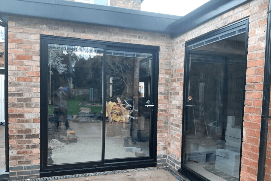 black uPVC inline sliding door old brick house